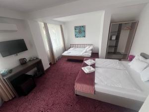 a hotel room with two beds and a flat screen tv at Pensiunea Simar in Sibiu