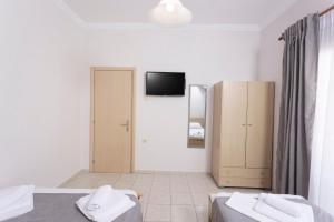 una camera con due letti e una TV a parete di Ice Hot Rooms Pefkochori a Pefkohori