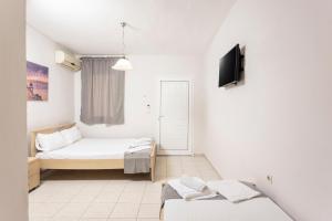 um quarto com duas camas e uma televisão na parede em Ice Hot Rooms Pefkochori em Pefkohori