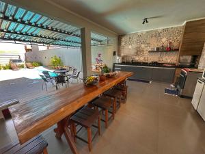 duża kuchnia z dużym drewnianym stołem i krzesłami w obiekcie casa inteira com 3 suites e área de lazer w mieście Delfinópolis