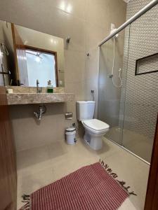 a bathroom with a toilet and a shower and a sink at casa inteira com 3 suites e área de lazer in Delfinópolis