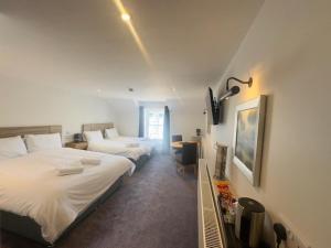 a bedroom with two beds and a desk with a lamp at The White Lion Hotel in Machynlleth