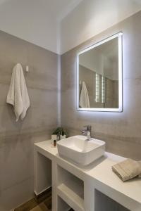 uma casa de banho com um lavatório branco e um espelho. em Studios Kymata em Pollonia