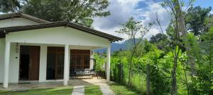 une petite maison blanche avec une terrasse couverte dans un jardin dans l'établissement Meegahasewana Bungalow, à Kurunegala