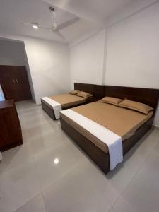 Meegahasewana Bungalow في كورونيغالا: سريرين في غرفة بجدران بيضاء