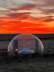 un igloo dans un champ avec un coucher de soleil en arrière-plan dans l'établissement Aurora Igloo, à Hella