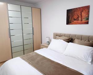 a bedroom with a white bed and a closet at Regis Apartment in Tirana