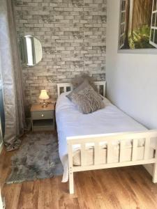 a bedroom with a white bed and a brick wall at Cosy and secluded brook-side lodge in Sleaford