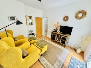 sala de estar con sofá amarillo y TV en Appartement Rosenwinkel, en Warnemünde