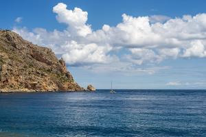 a sail boat in the ocean next to a cliff at Port de Xabia V in Jávea