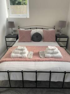 a large bed with two pillows and towels on it at Willow Lodge in Dymchurch