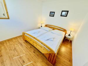 1 dormitorio con cama de madera con sábanas blancas en Appartement Rosenwinkel, en Warnemünde