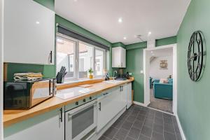 uma cozinha com armários brancos e paredes verdes em The Cottage at Logan Lodge em Great Yarmouth