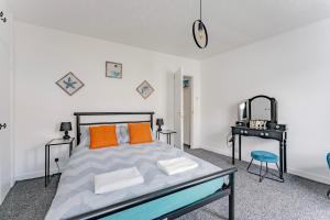 um quarto com uma cama com almofadas laranja e uma secretária em The Cottage at Logan Lodge em Great Yarmouth