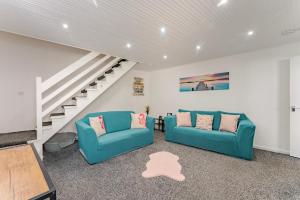 a living room with two blue couches and a staircase at The Cottage at Logan Lodge in Great Yarmouth