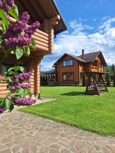 una casa de madera con flores púrpuras en el patio en Khytir Falchi en Mykulychyn