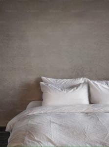 1 cama con sábanas blancas y almohadas contra la pared en Sole Boutique Hotel en Vipiteno