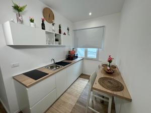 a kitchen with white cabinets and a table and a sink at Casa Belfiore Etna-apartments in Giarre