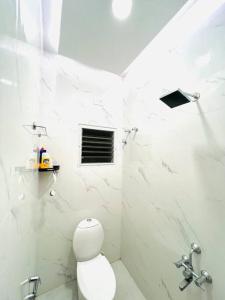 a white bathroom with a toilet and a shower at HemaRay villa - luxury stay with pool in Chennai