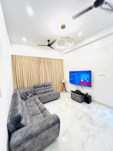 a living room with a couch and a flat screen tv at HemaRay villa - luxury stay with pool in Chennai