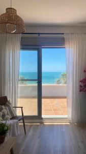 ein Wohnzimmer mit einem großen Fenster mit Meerblick in der Unterkunft Ático Al Sol en primera línea de playa in Rota