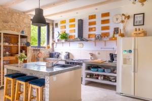 a kitchen with a refrigerator and a counter with stools at La Grange des Anges in Blanc