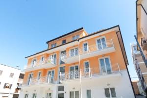 un edificio naranja con balcones blancos en una calle en Resort Cupra, en Cupra Marittima