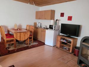 a kitchen with a table and a refrigerator and a television at Ferienwohnung 500m zum See in Vollrathsruhe