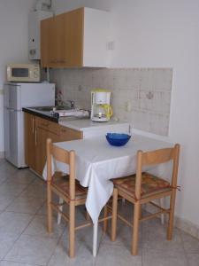eine Küche mit einem Tisch, 2 Stühlen und einer Theke in der Unterkunft Angenehme Ferienwohnung mit Balkon, umgeben von einem Garten in Banjole