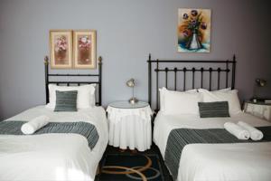 1 dormitorio con 2 camas individuales y sábanas blancas en Janke Guest House en Kuruman