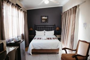 una camera da letto con letto, lenzuola e cuscini bianchi di Janke Guest House a Kuruman