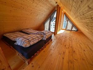 um quarto com uma cama num quarto de madeira com janelas em Kolorowe Domki nad Narie em Pojezierce