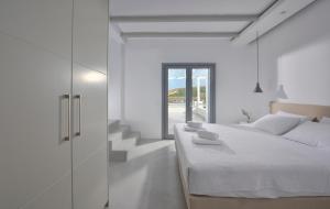 Villa Sapphire by Blanco Villas في Megali Ammos: غرفة نوم بيضاء بسرير ودرج