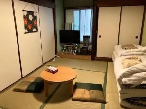 a room with two beds and a table and a television at わがらん家 -えんつなぎ- in Kumano