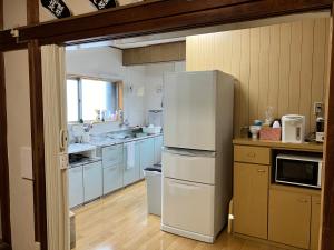 a kitchen with a white refrigerator in a room at わがらん家 -えんつなぎ- in Kumano