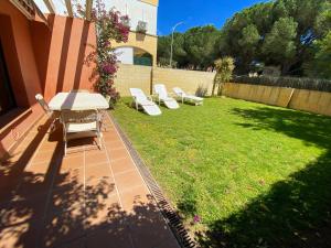 een achtertuin met een tafel en stoelen en een gazon bij Casa l'Escala, piscina comuntària i jardí privat in L'Escala