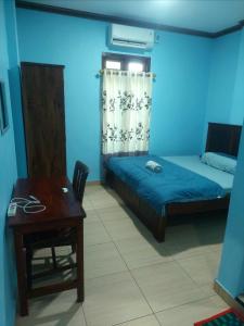 a bedroom with a bed and a desk and a table at D'Ru Guest House in Labuan Bajo