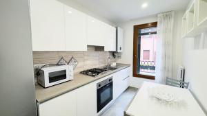 a white kitchen with a microwave and a stove at Casa Venturini by Ca-Sa Check in Chioggia