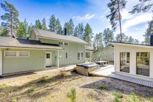a green house with a patio next to a house at Holiday Cabin Mäntyhovi in Kalajoki