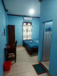 1 dormitorio con paredes azules, 1 cama y 1 mesa en D'Ru Guest House en Labuan Bajo