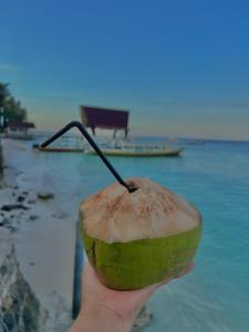 a person holding a green apple with a stick in it at Bronze Bungalows in Gili Meno
