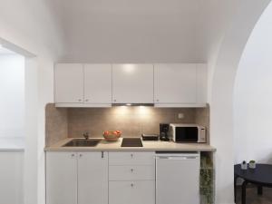 a white kitchen with a sink and a microwave at Elegant, affordable apartment with a fireplace in Athens