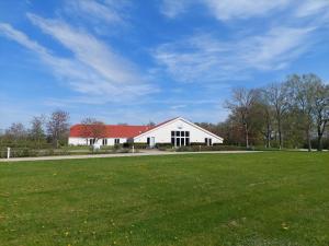 a large white barn with a red roof on a field at Læsø Efterskole in Læsø