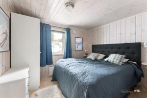 1 dormitorio con 1 cama y una ventana con cortinas azules en Nesfjellet, en Nes i Ådal