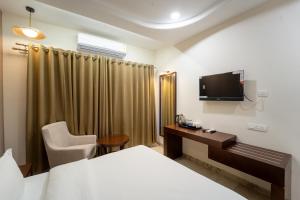 a hotel room with a bed and a desk and a tv at Krishna Inn in Aurangabad