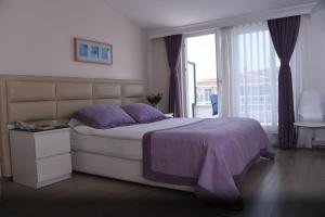 Un dormitorio con una cama con sábanas moradas y una ventana en A Hotels & Suite en Ankara