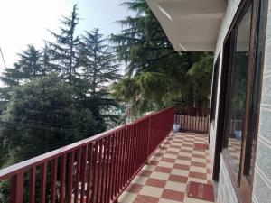a balcony of a house with a red fence and trees at DREAM HILLS B&B in Dalhousie