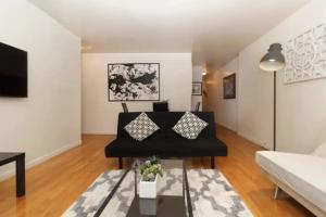ein Wohnzimmer mit einem schwarzen Sofa und einem Tisch in der Unterkunft 2Bed Bliss by Central Park North in New York