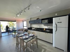 a kitchen with a table and a white refrigerator at Altamare - Pé na areia in Tambaú