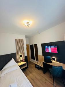 a bedroom with a bed and a desk and a tv at Hotel Stadt Emmerich in Emmerich